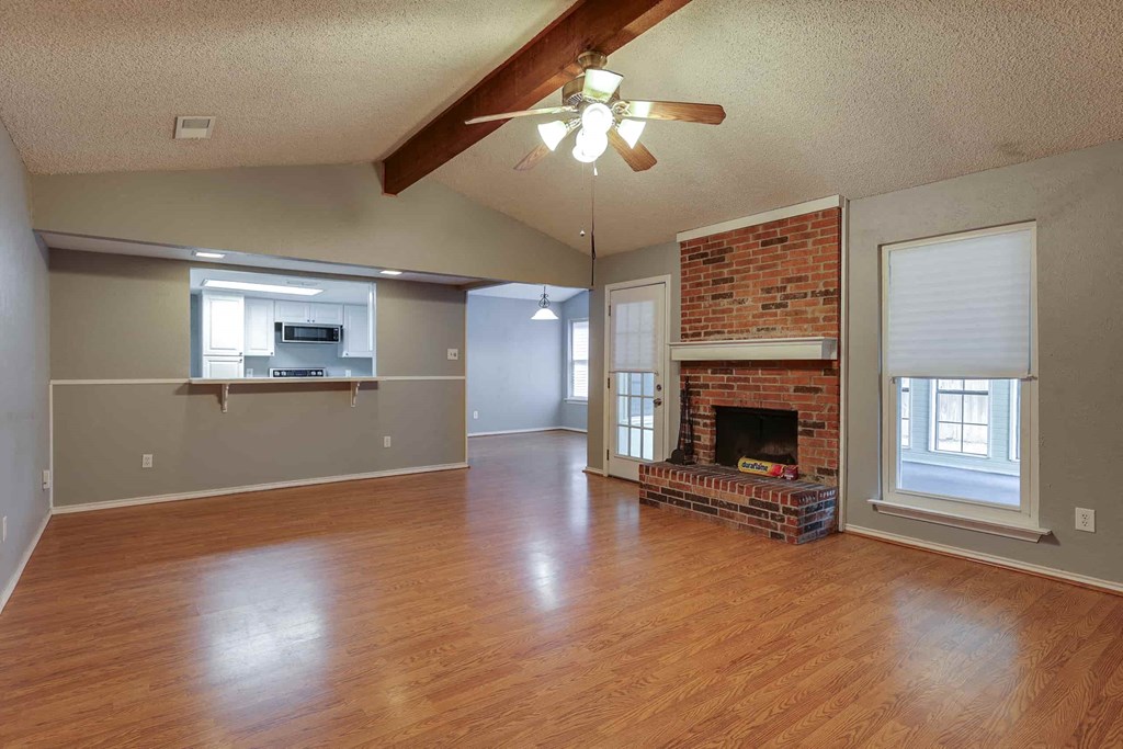 an empty living room with a fireplace and a ceiling fan