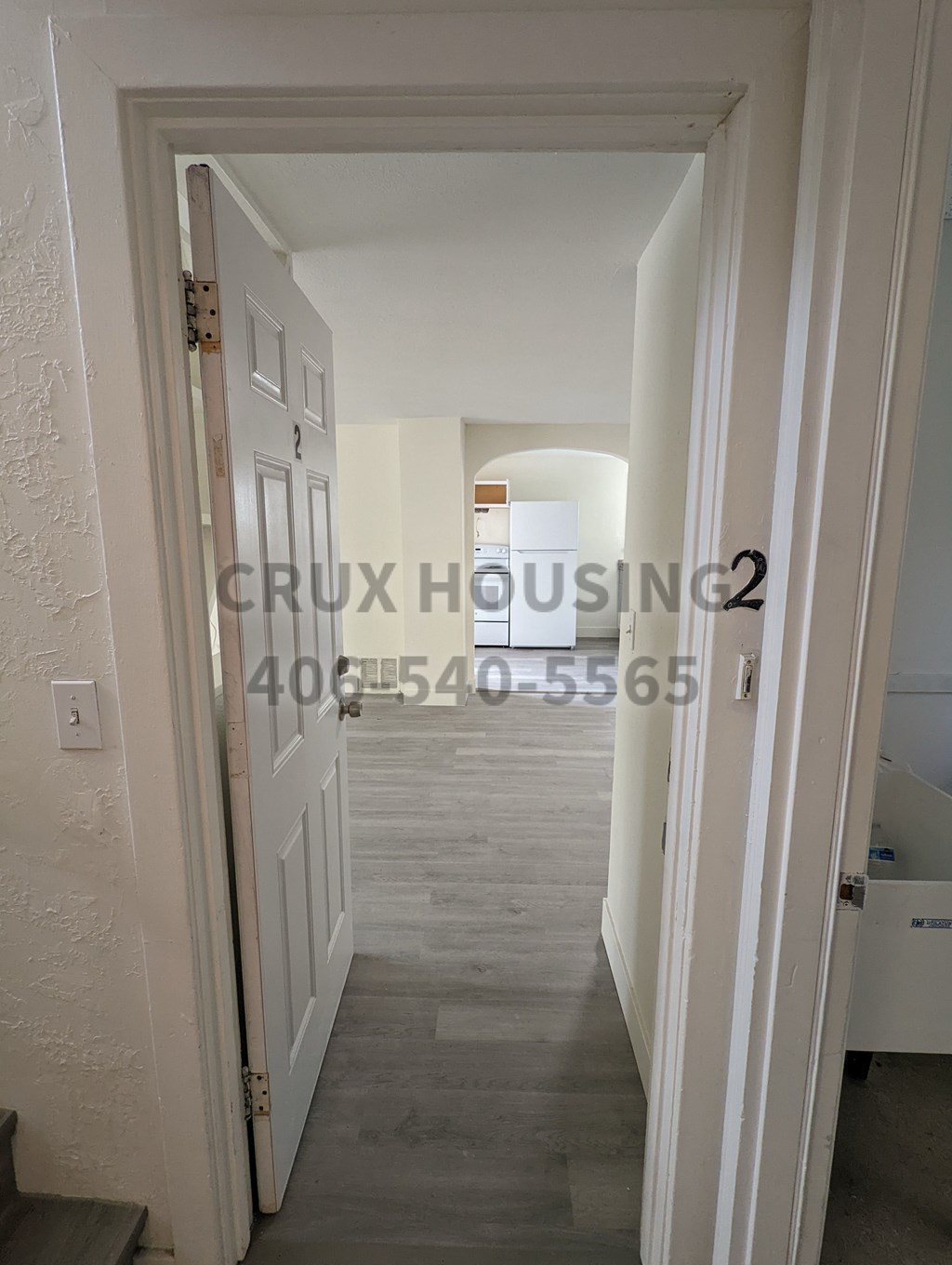 A white doorway leading to a hallway with a light switch on the wall.