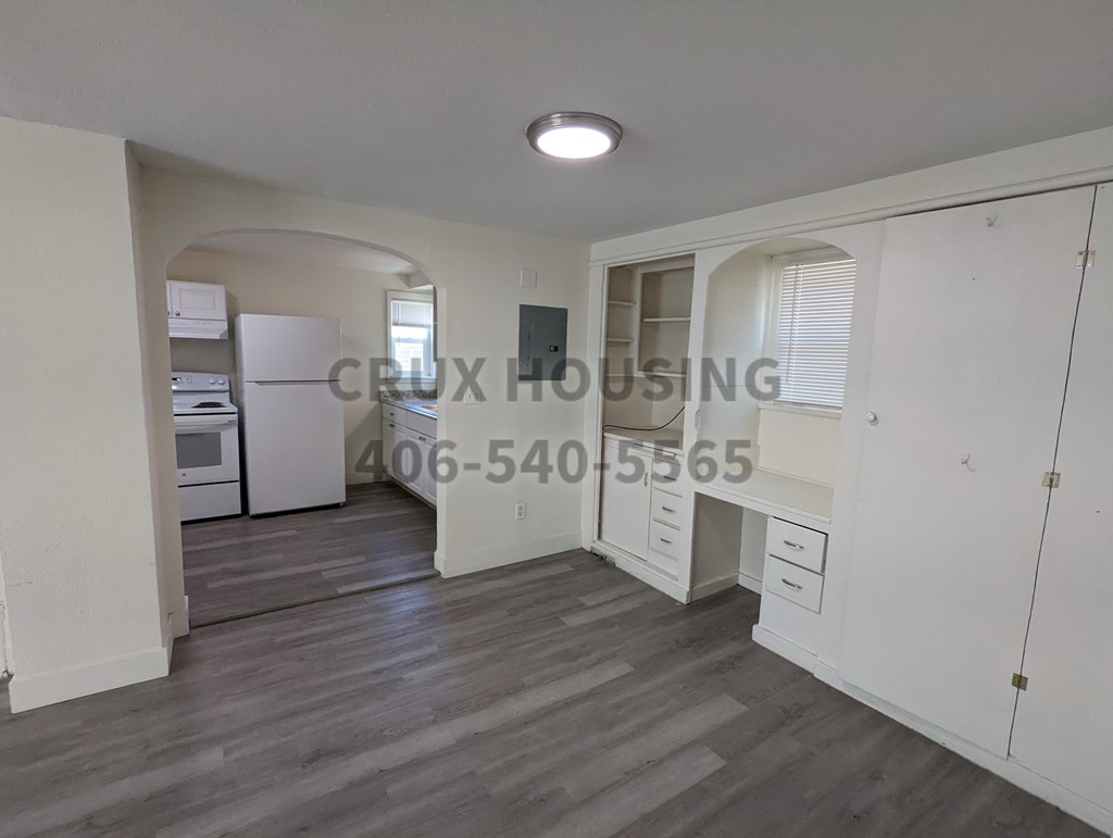A kitchen with white appliances and a phone number on the wall.