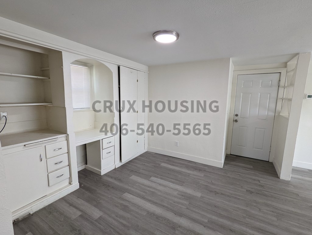 A room with a white door and a white wall with the text "CRUX HOUSING" and a phone number on it.