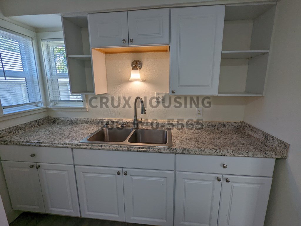 A kitchen with a granite countertop and white cabinets.