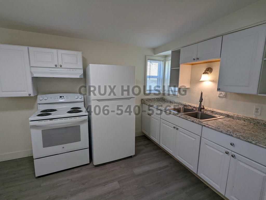 A kitchen with white cabinets and a stove top oven.