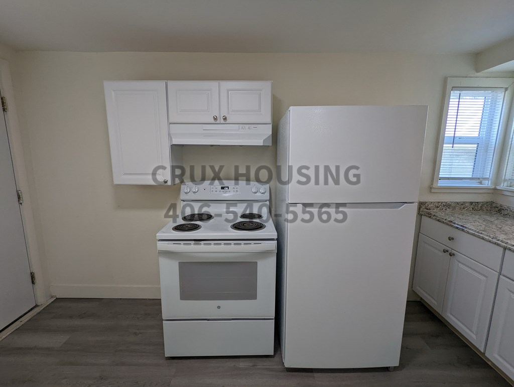 A kitchen with a white fridge, stove and cabinets.