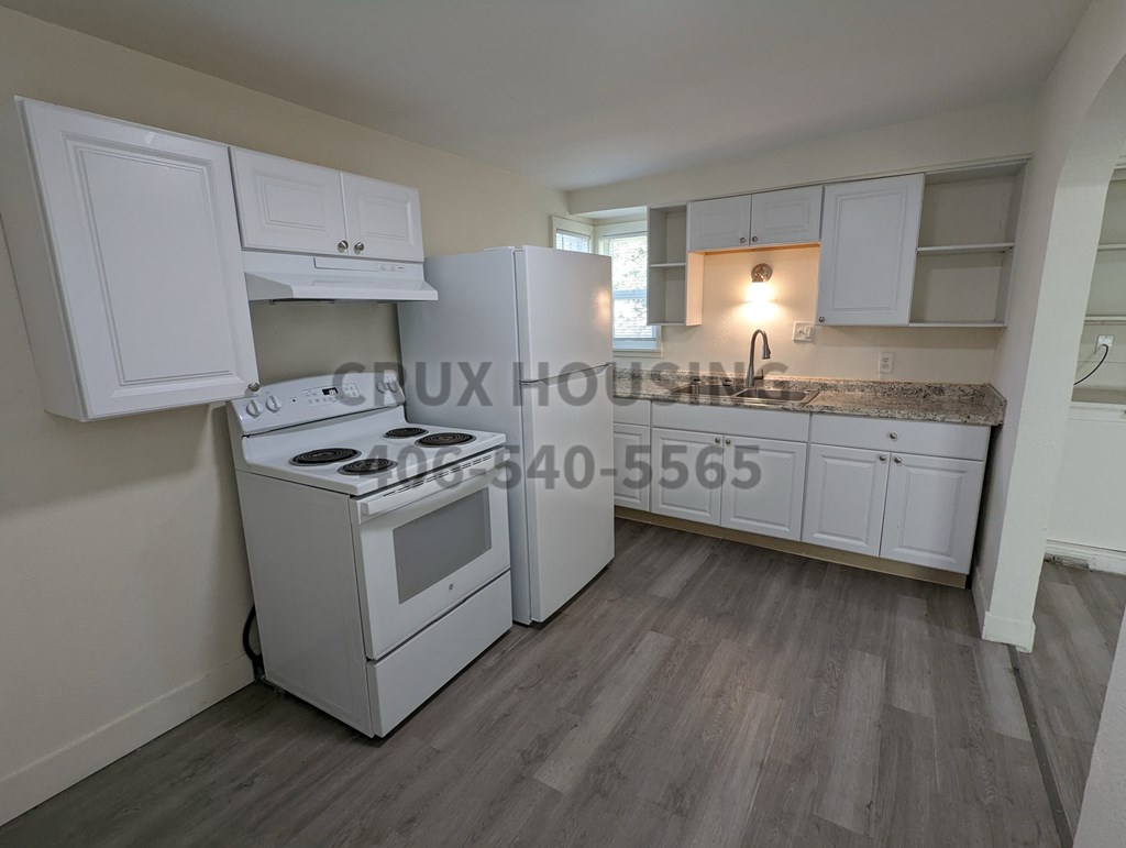 A kitchen with white cabinets and a stove top oven.