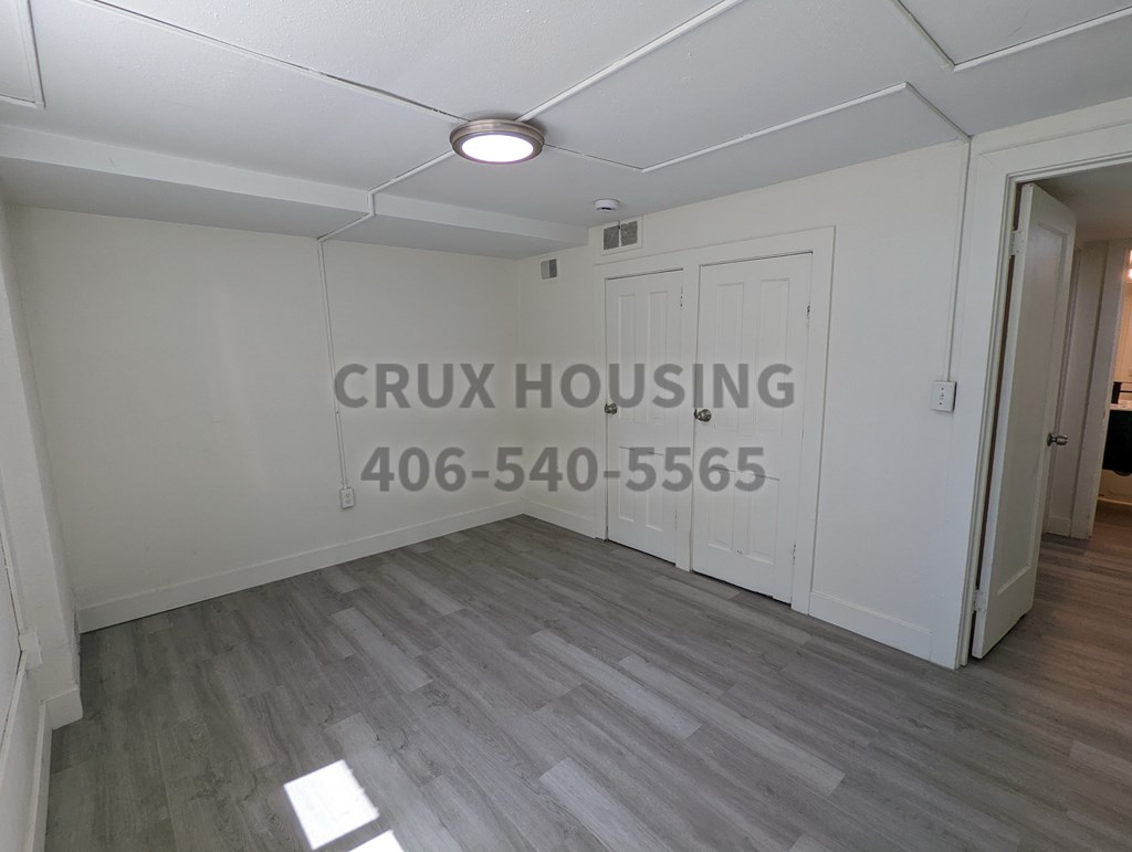 A room with a sign that says "CRUX HOUSING" and a phone number on the wall.