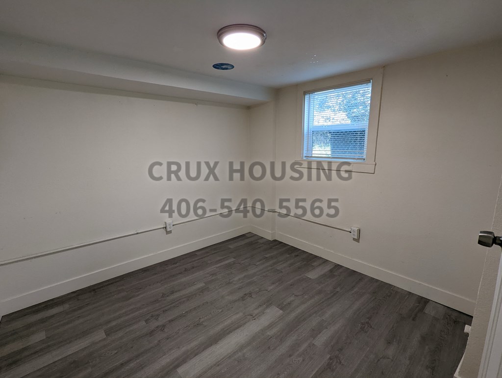 A room with a window and a wooden floor.