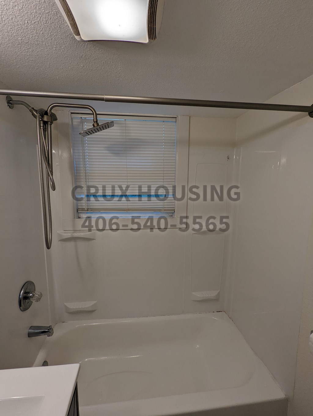 A white bathtub in a bathroom with a shower head and a window.