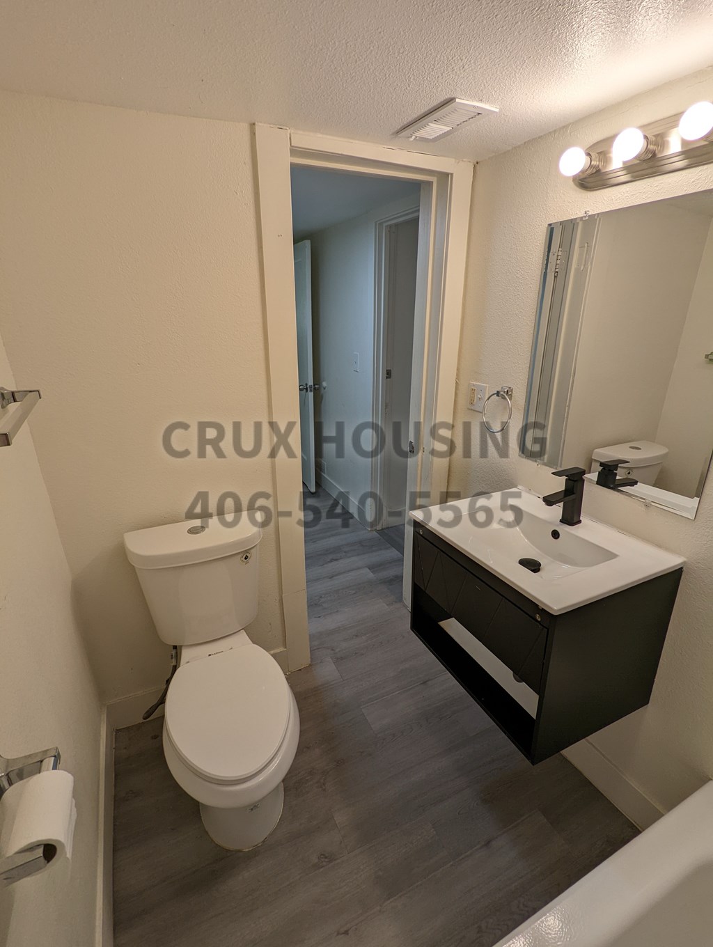 A bathroom with a toilet, sink, and mirror.