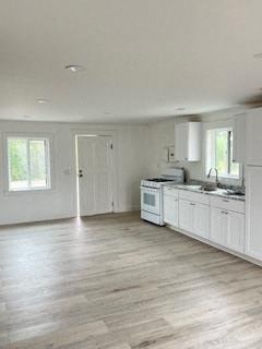 an empty kitchen with white cabinets and a sink