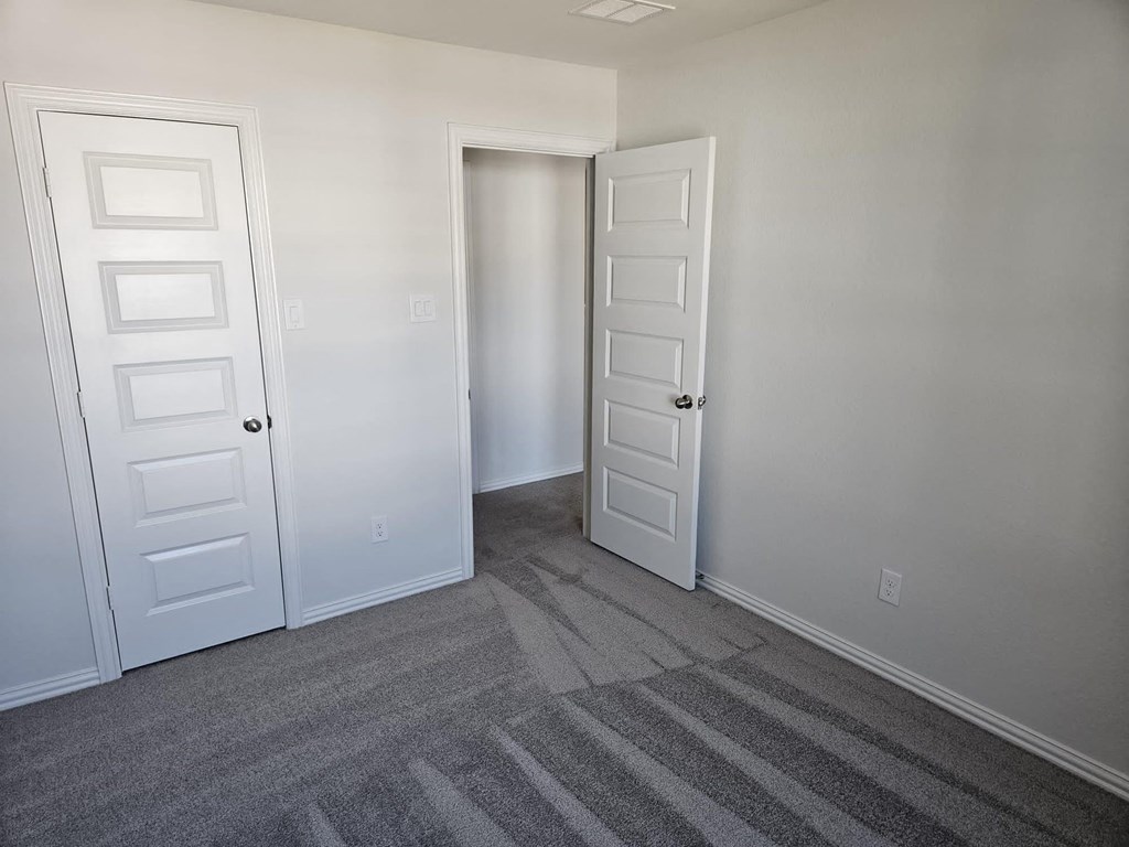 a bedroom with two doors and a carpeted floor