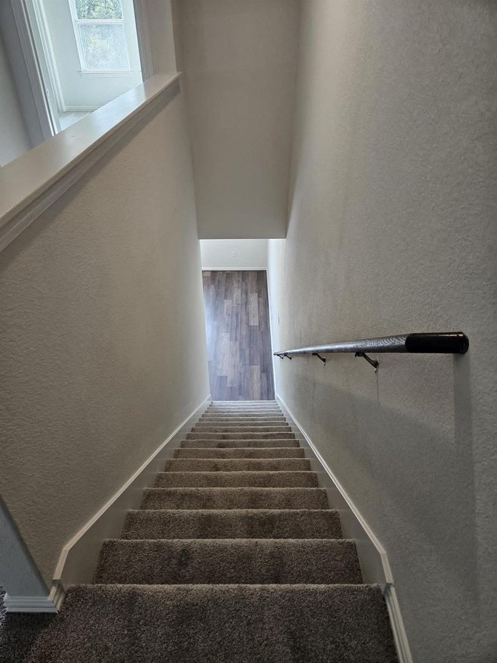 a flight of stairs with a hand rail and a window