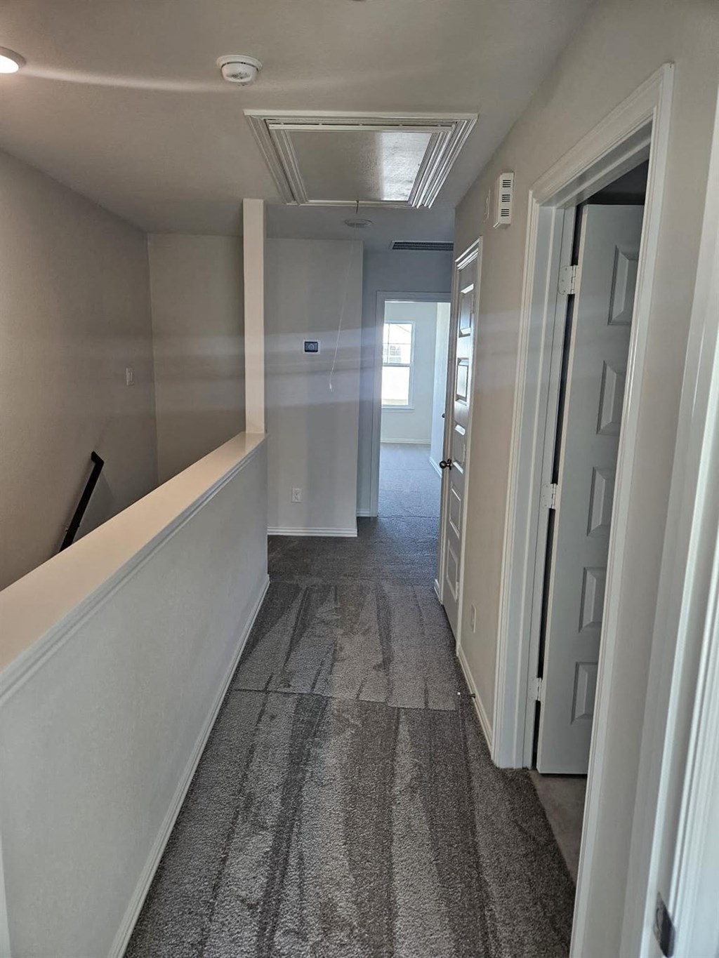 a hallway with a carpeted floor and white walls and a door