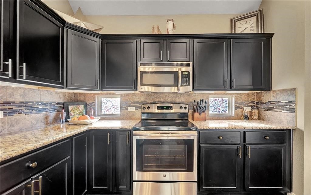 a kitchen with black cabinets and stainless steel appliances