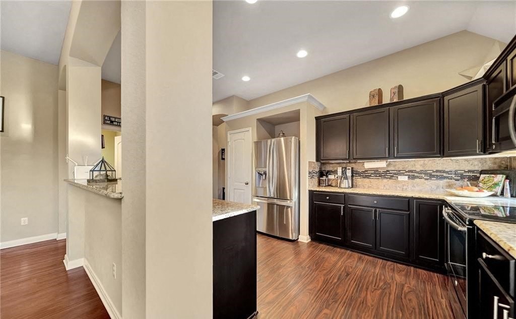 a kitchen with black cabinets and a stainless steel refrigerator