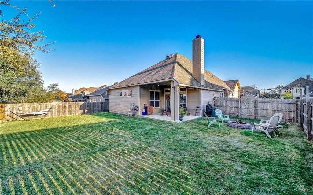 a backyard with a house and a yard with a lawn and chairs