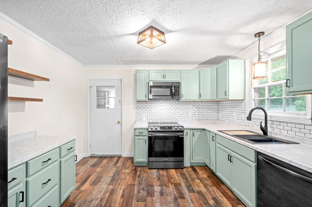 a kitchen with green cabinets and a stove and a sink
