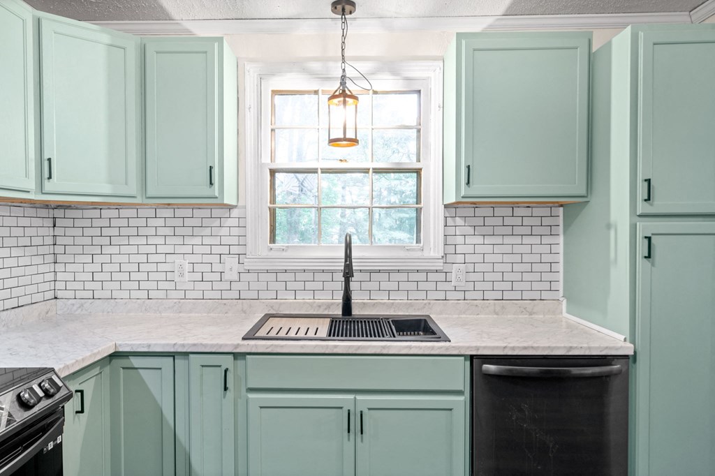 a kitchen with green cabinets and a sink and a window