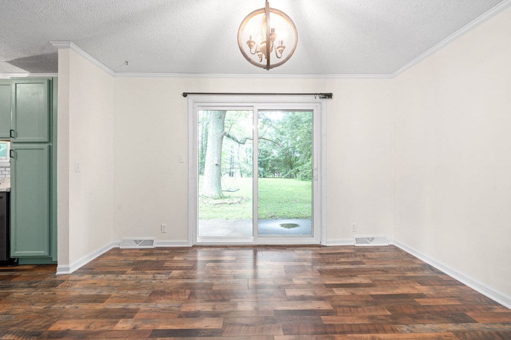 an empty living room with a sliding glass door to a yard