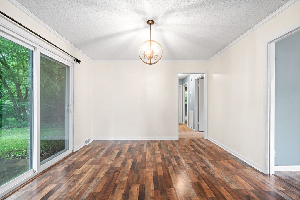 an empty living room with wood floors and a large window