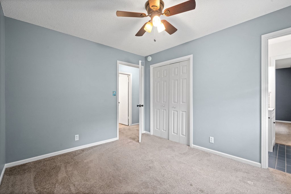 an empty living room with blue walls and a ceiling fan