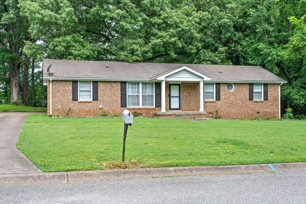 a small brick house with a parking meter in the grass