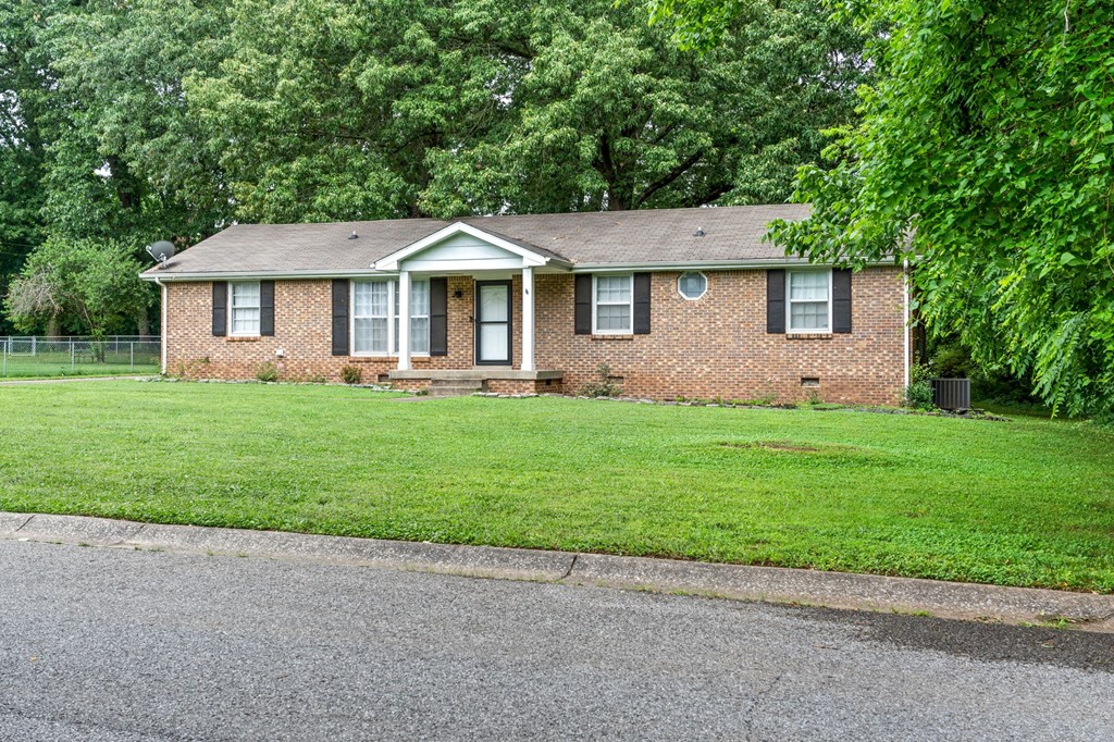 a small brick house with a lawn and a fence