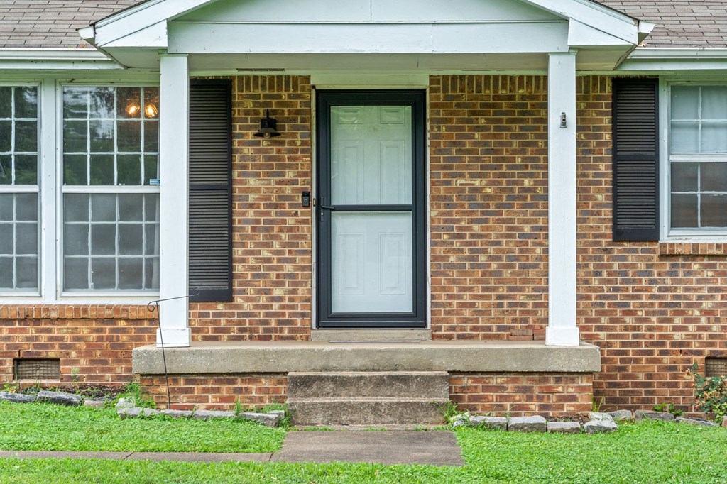 a front porch of a brick house with a white door