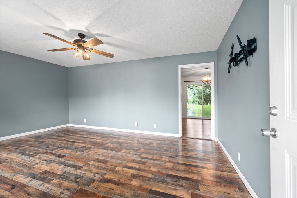 an empty living room with wood flooring and a ceiling fan