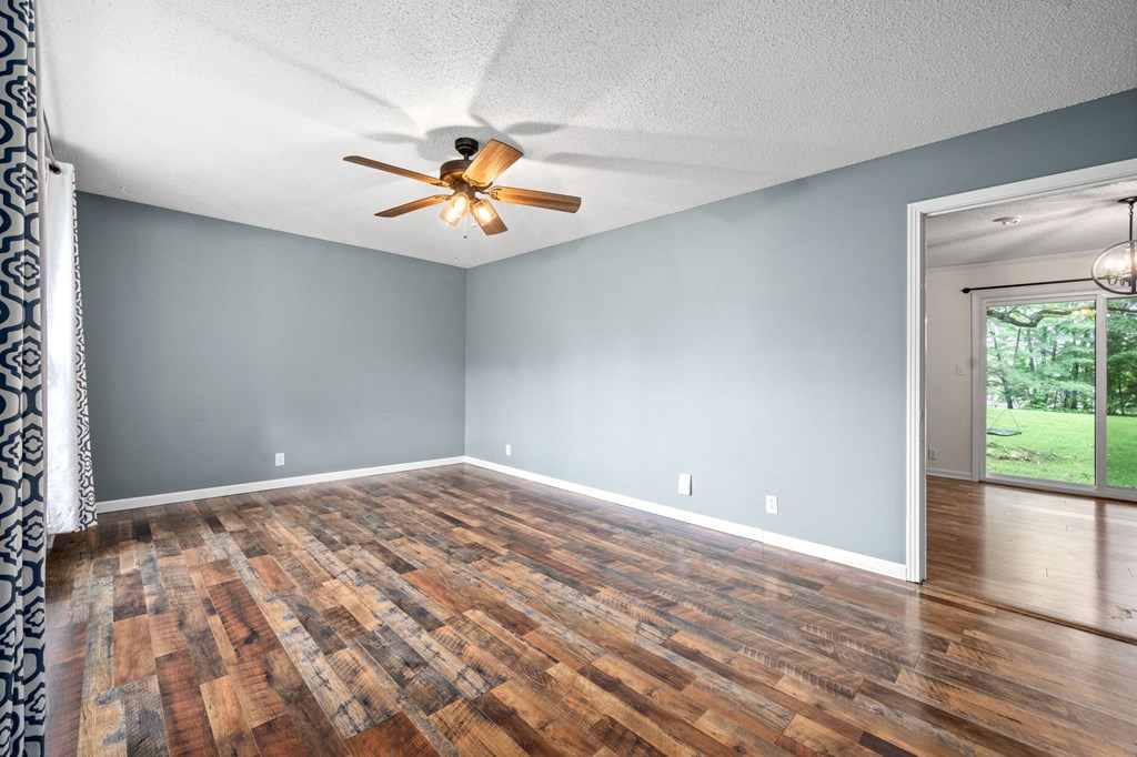 an empty living room with wood floors and a ceiling fan