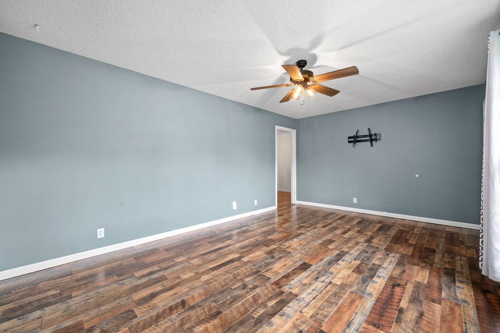 the living room with wood floors and a ceiling fan