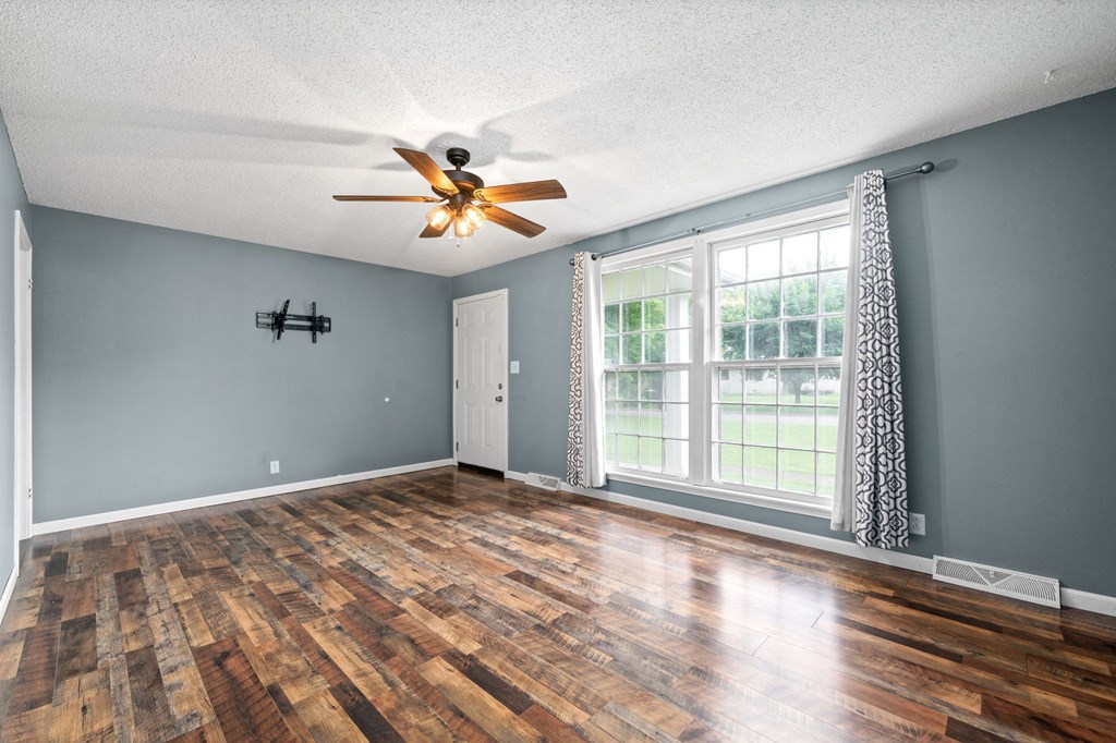 an empty living room with wood floors and a ceiling fan