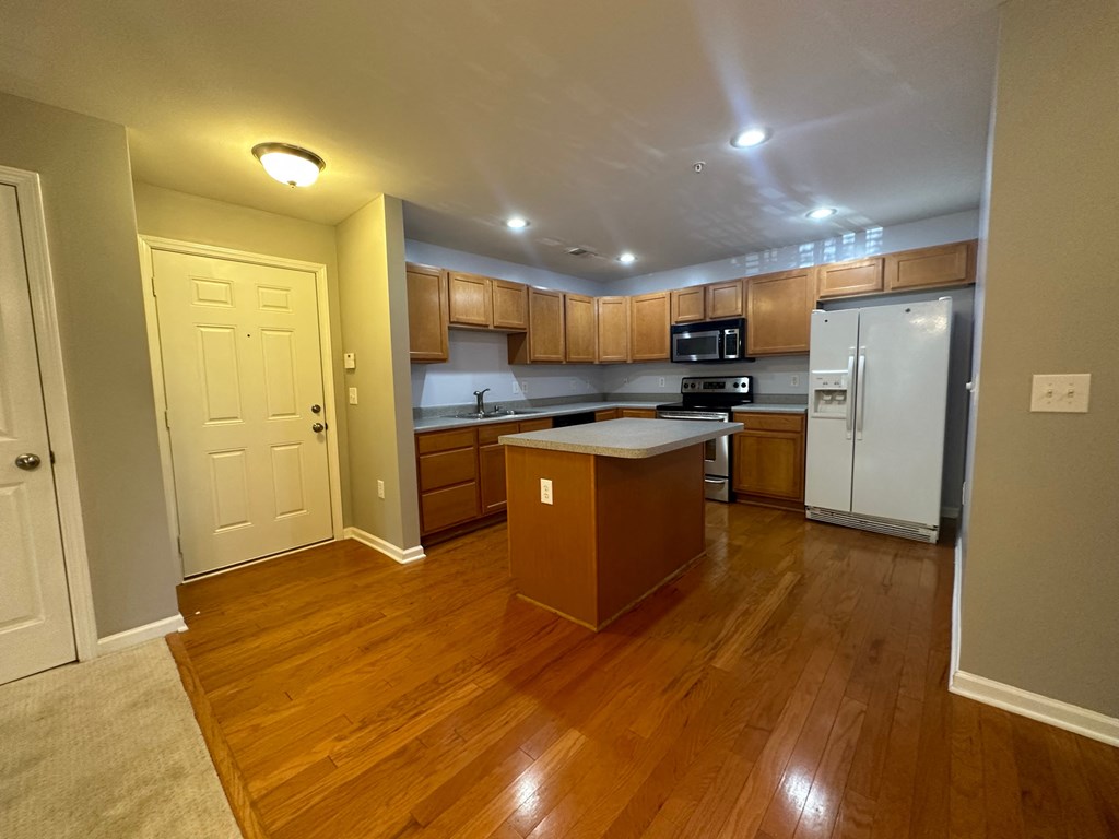 an empty kitchen with wooden floors and stainless steel appliances
