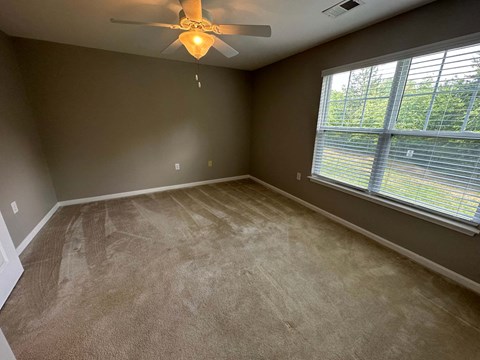 a living room with a large window and a ceiling fan