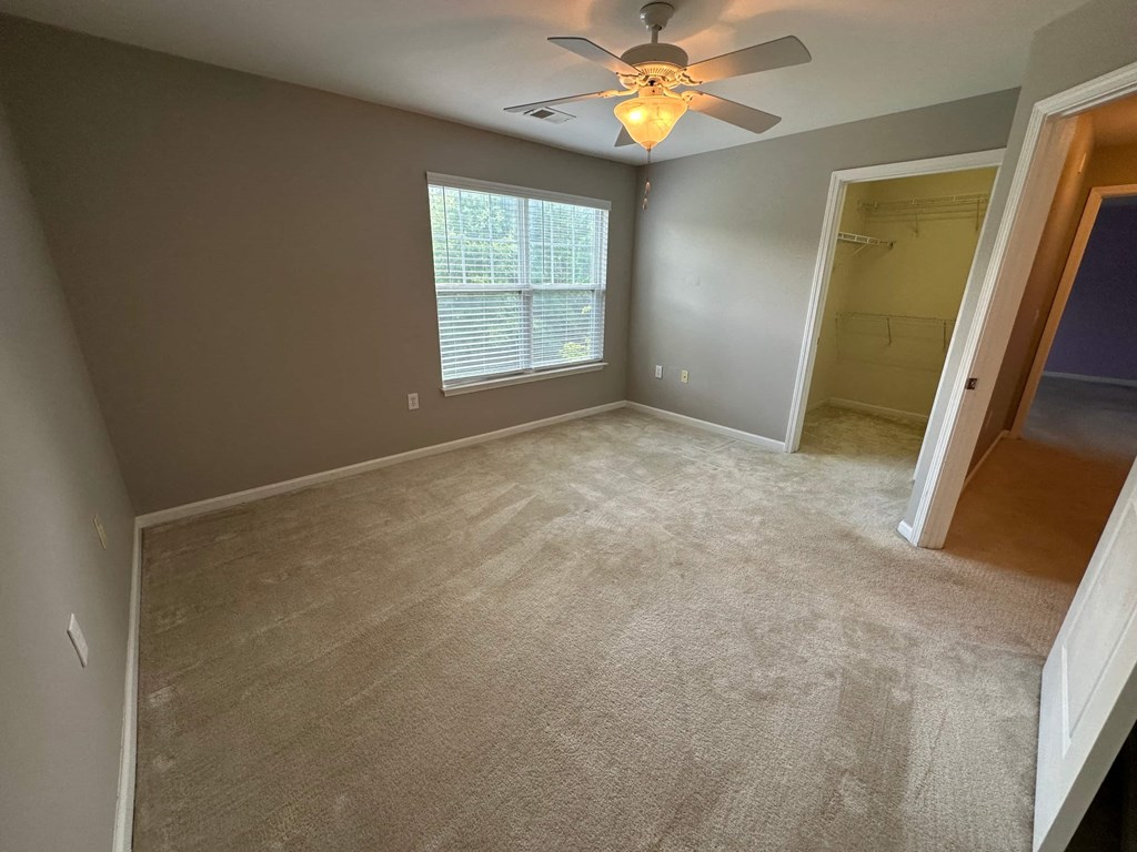 a empty living room with a ceiling fan and a window