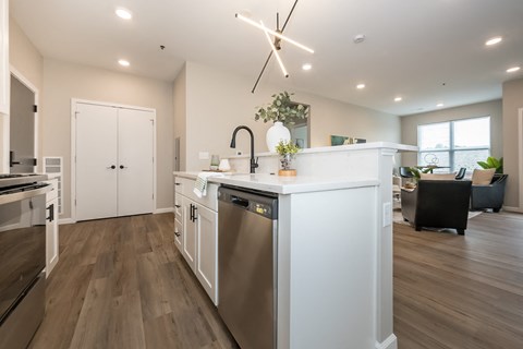 a white kitchen with a large counter top and a stainless steel dishwasher