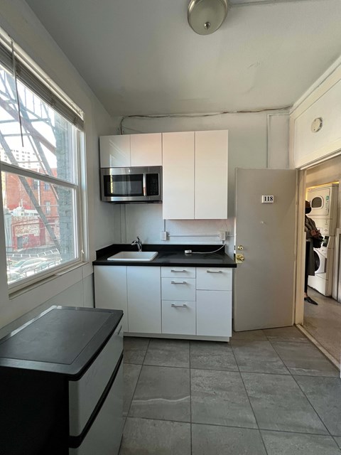 A kitchen with white cabinets and a black countertop.
