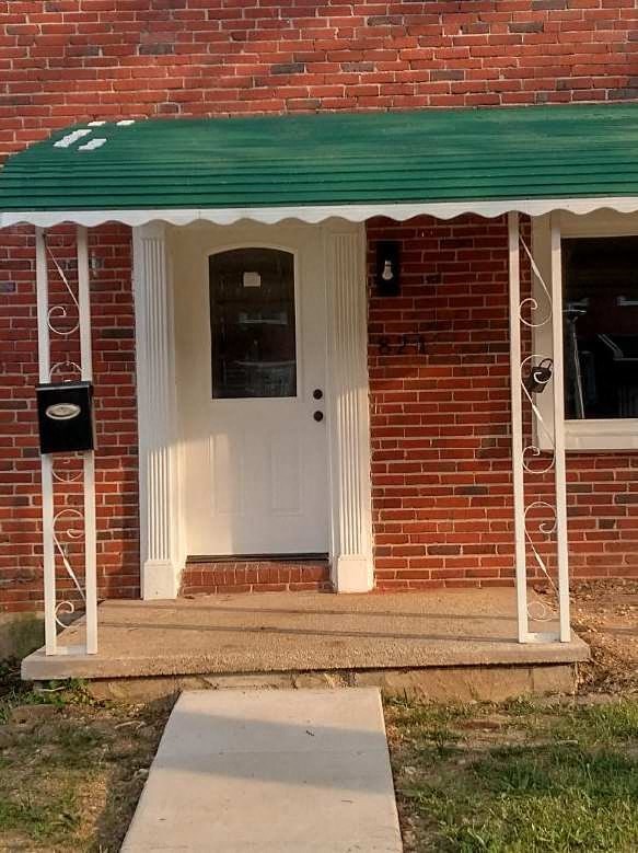 a brick building with a white door and a green roof