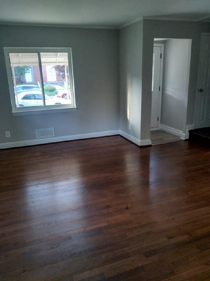 an empty living room with wooden floors and a window