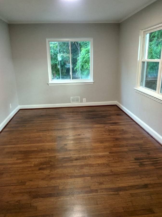 a empty room with a wooden floor and two windows