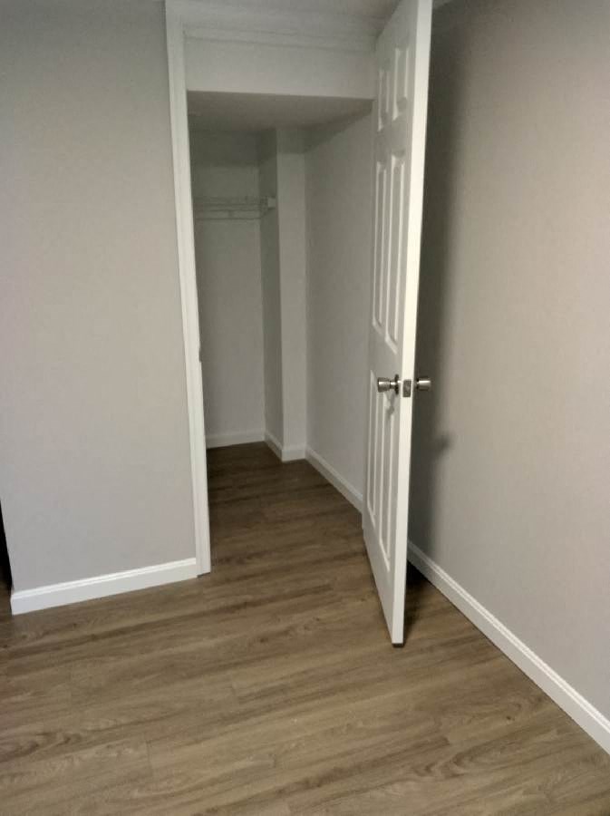 a room with a door and a hallway with wood floors