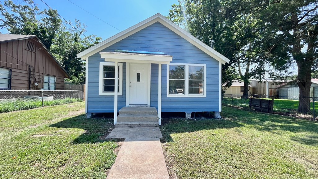 a small blue house with a sidewalk in front of it