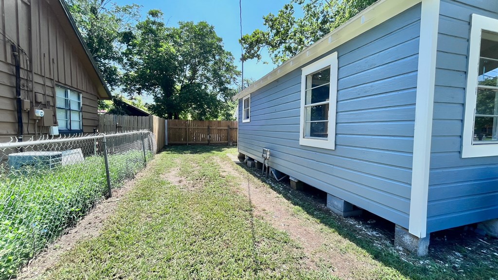 a blue house with a yard and a fence next to it