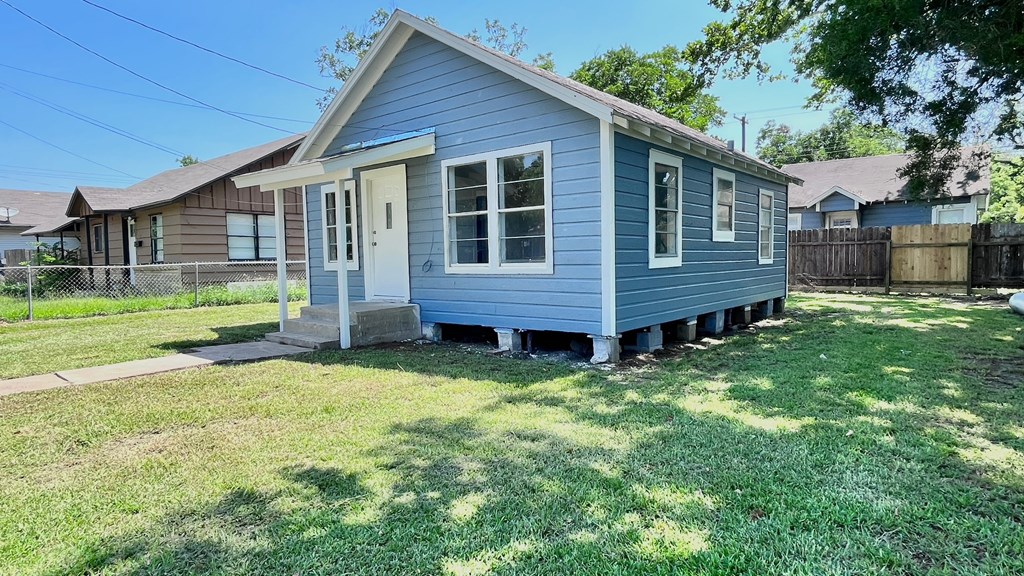 a small blue house with a yard and a fence