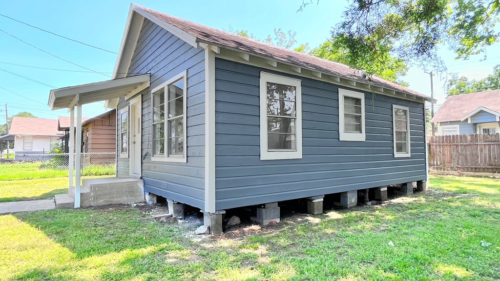 a small blue house with a yard and a fence