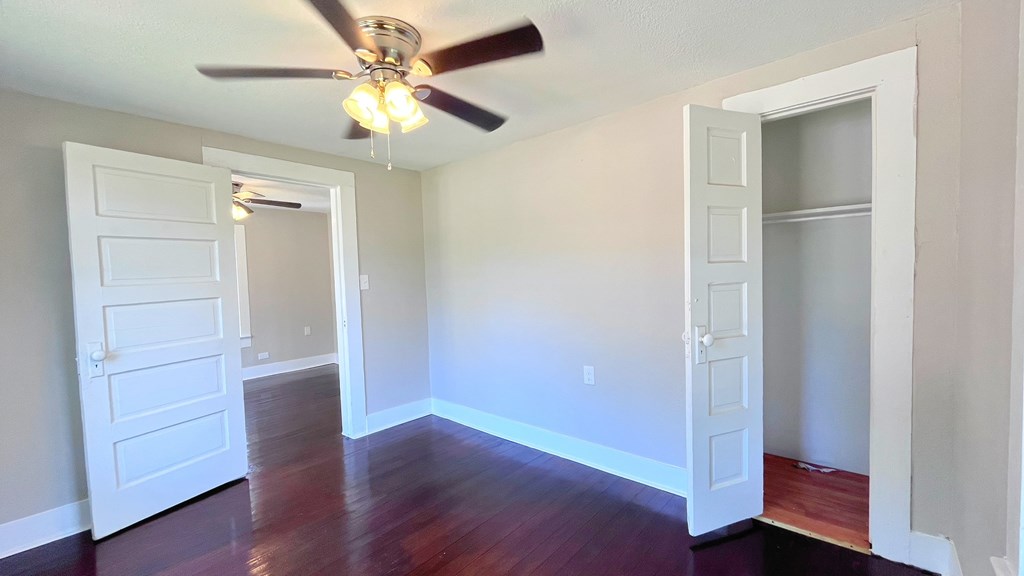 an empty living room with wood floors and a ceiling fan