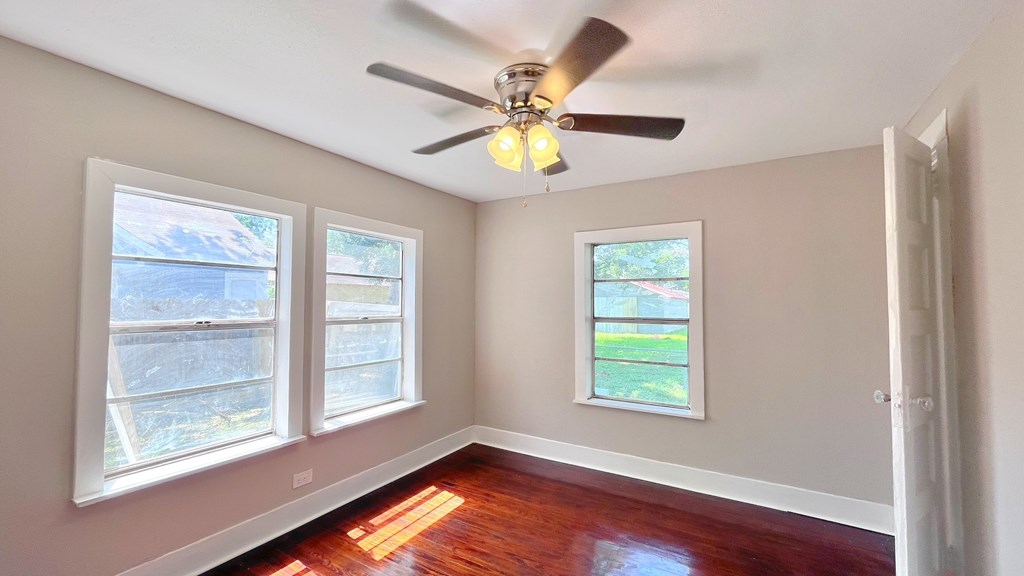 an empty room with a ceiling fan and three windows