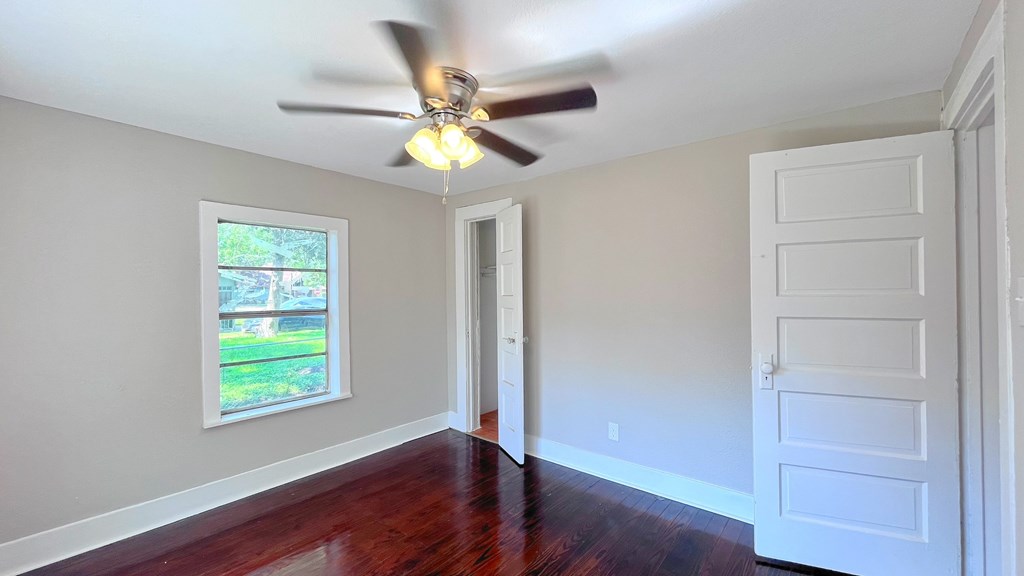 an empty living room with a ceiling fan and a window