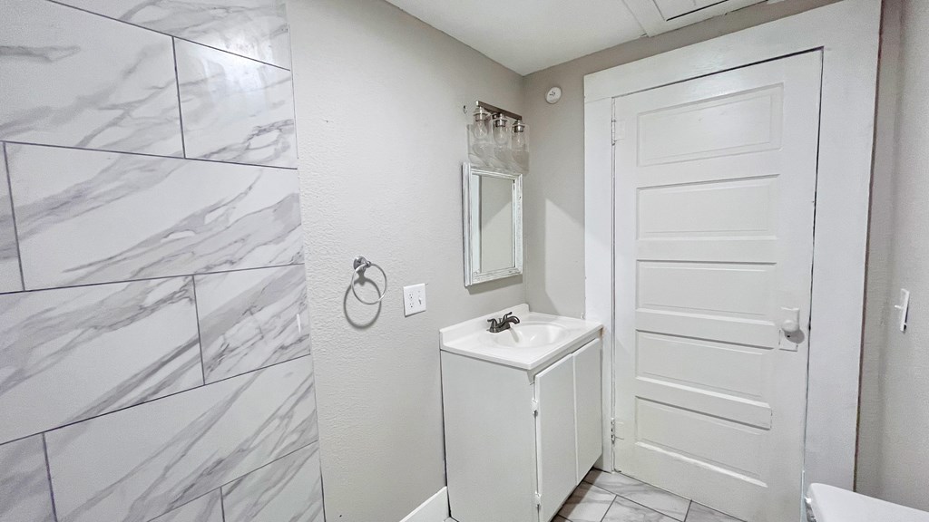 a white bathroom with a sink and a white door