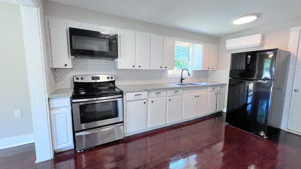 an empty kitchen with stainless steel appliances and white cabinets