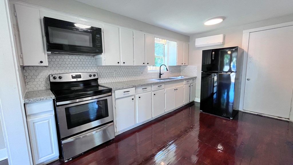 an empty kitchen with stainless steel appliances and white cabinets